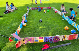 die bunt gestaltete Ballbande auf dem Rasen des Olympiastadions in Berlin und drumherum sitzen Menschen und chillen